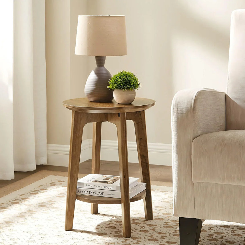 A round wood accent table styled with a lamp, books, and a plant.